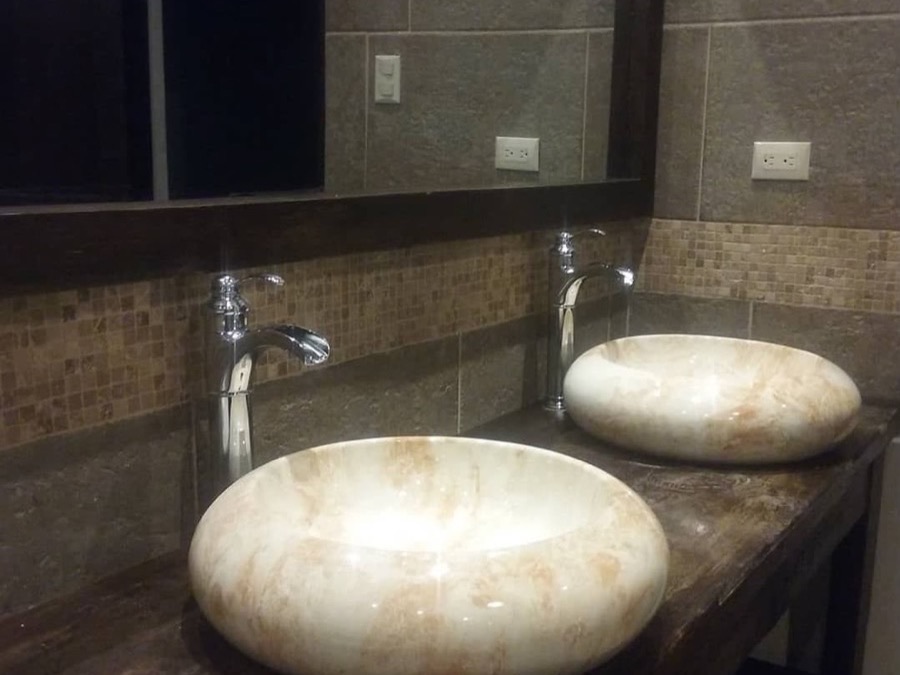 Lavamanos de piedra y espejo con marco de madera de una obra de BR Constructora