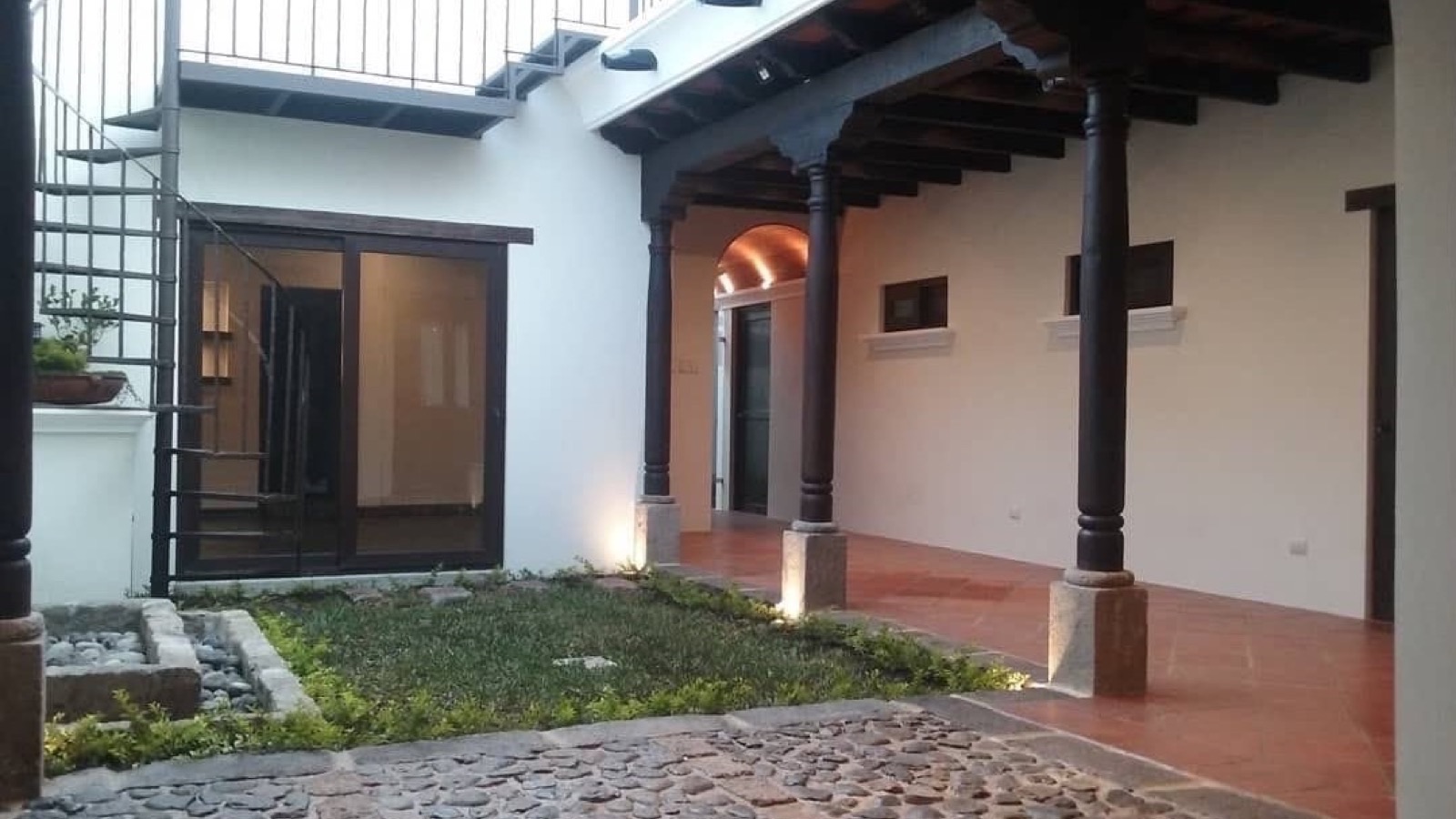 Patio colonial con columnas de madera de una obra de BR Constructora