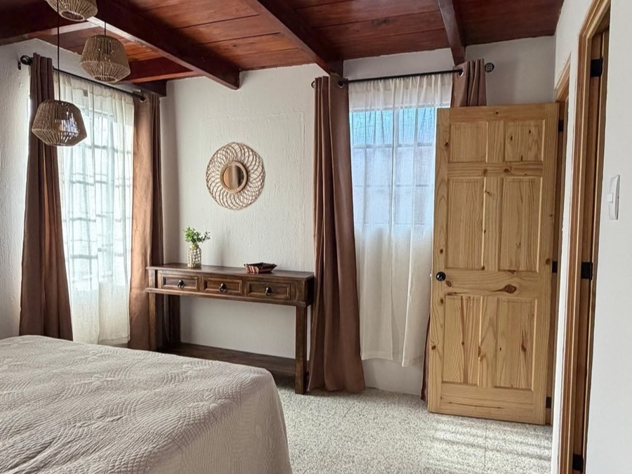 Dormitorio con cielo de vigas de madera y puerta de pino de una obra de BR Constructora