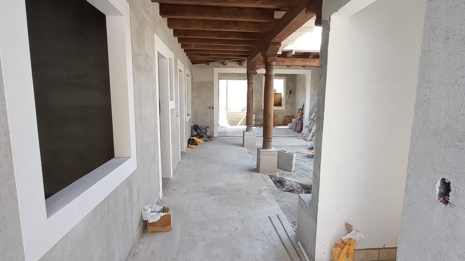 Pasillo en construcción con vigas de madera y columnas coloniales de una obra de BR Constructora